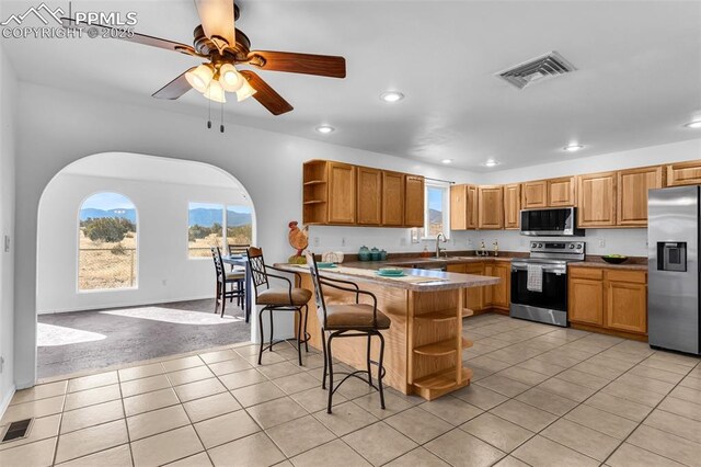 kitchen with a breakfast bar area, open shelves, stainless steel appliances, visible vents, and a peninsula