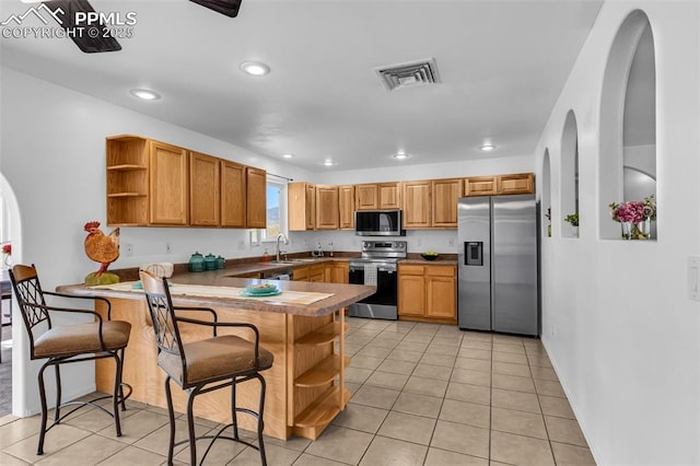 kitchen featuring open shelves, visible vents, appliances with stainless steel finishes, a sink, and a peninsula