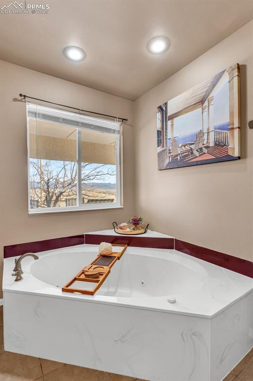 full bathroom with a tub with jets and tile patterned floors