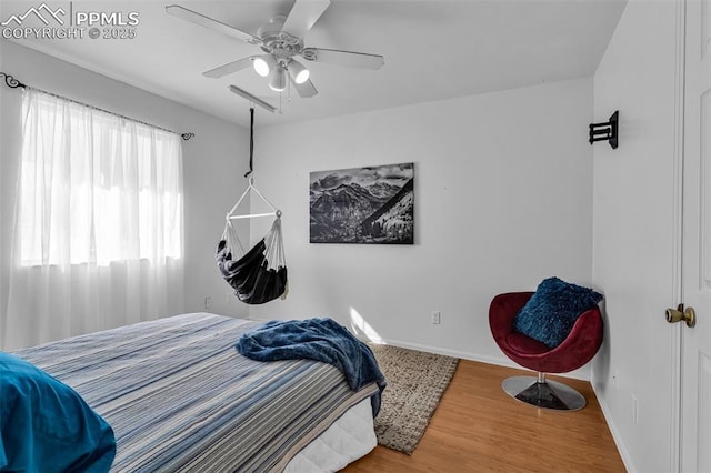 bedroom featuring a ceiling fan, baseboards, and wood finished floors