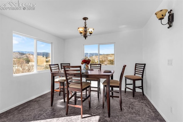 carpeted dining space with an inviting chandelier, baseboards, and a mountain view