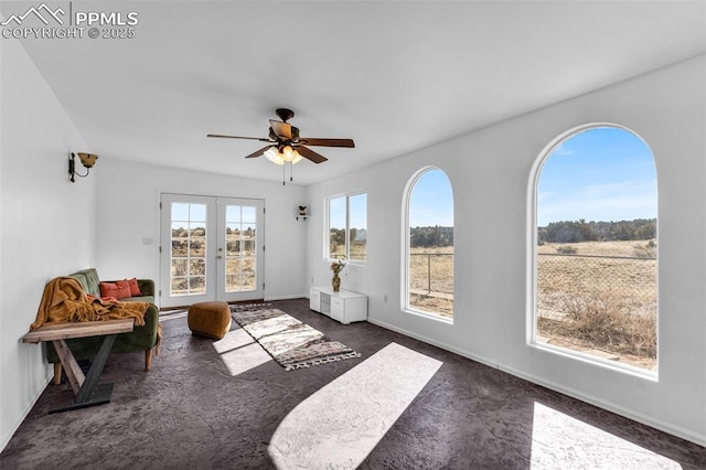 living area with a healthy amount of sunlight, ceiling fan, dark colored carpet, and french doors