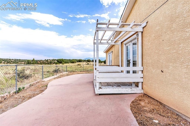 view of home's exterior with french doors, a patio, stucco siding, fence, and a pergola