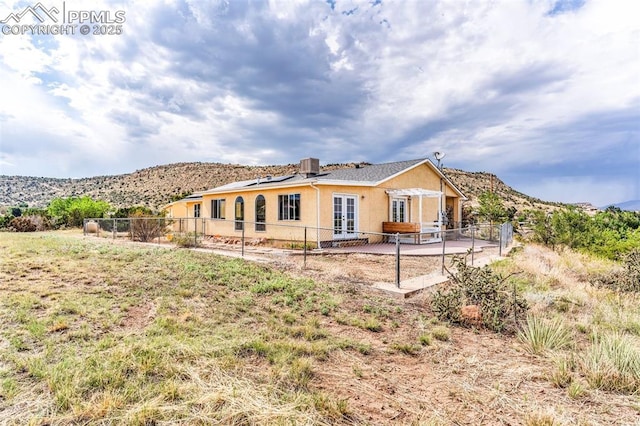 rear view of house with french doors, stucco siding, a patio area, a mountain view, and a fenced backyard