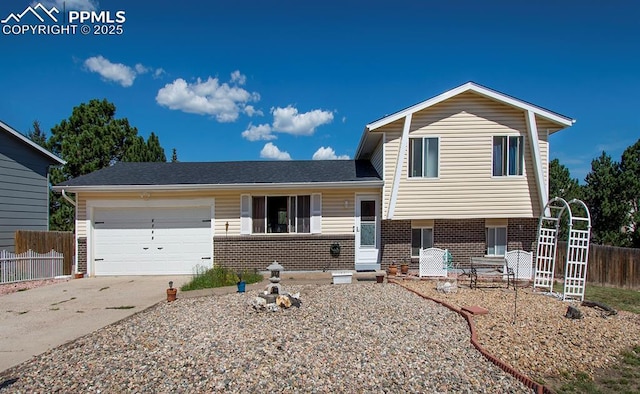 tri-level home featuring brick siding, driveway, an attached garage, and fence