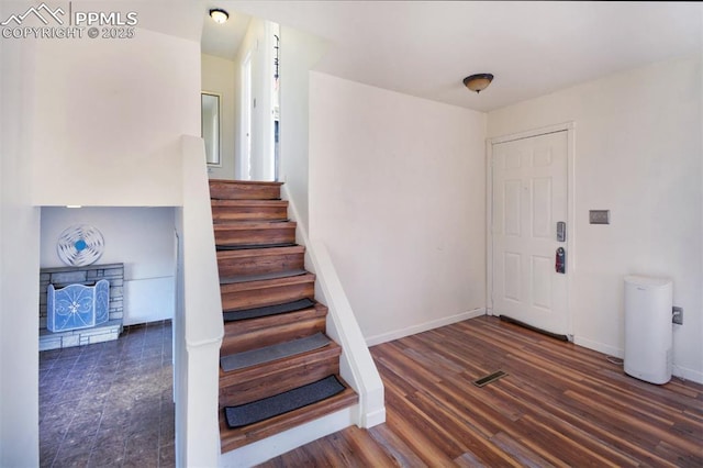 entryway with stairway, a fireplace, wood finished floors, and baseboards