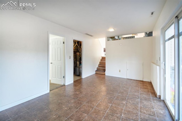 unfurnished room with stairway, visible vents, and baseboards