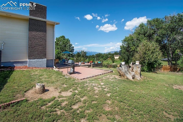 view of yard featuring a mountain view, a patio, and fence