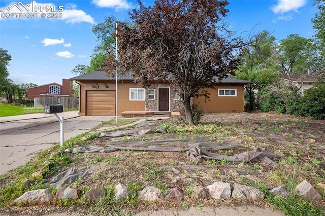 view of front of house featuring a garage, fence, driveway, stone siding, and stucco siding