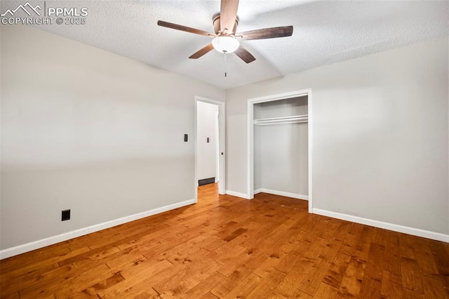 unfurnished bedroom with light wood-style floors, a closet, baseboards, and a textured ceiling