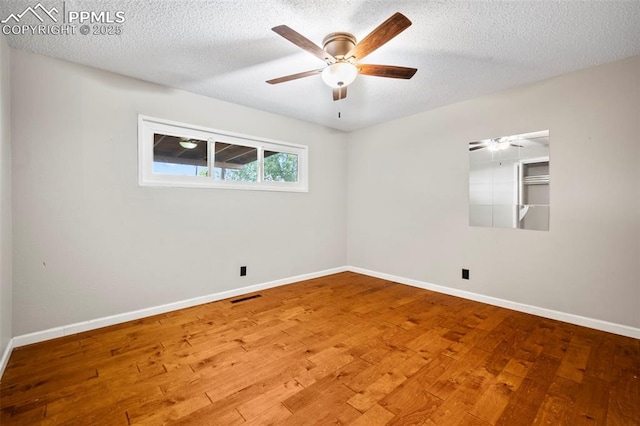 empty room with visible vents, baseboards, wood-type flooring, ceiling fan, and a textured ceiling