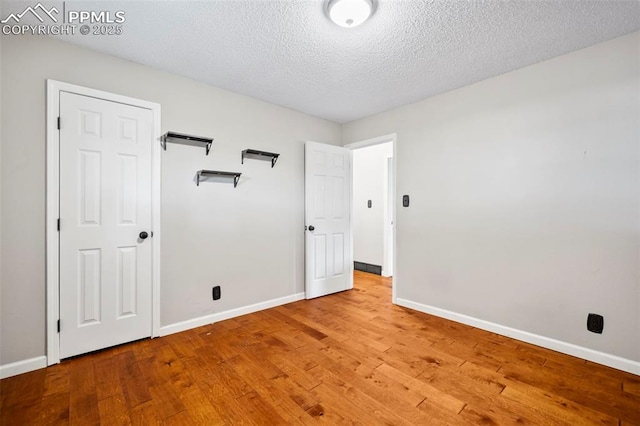 unfurnished bedroom featuring a textured ceiling, wood finished floors, and baseboards