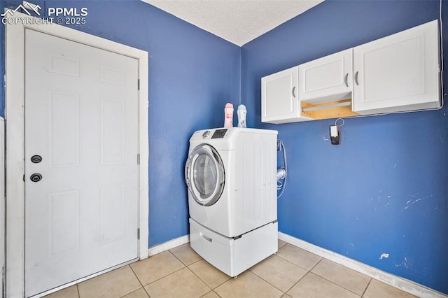 washroom featuring washer / clothes dryer, light tile patterned flooring, cabinet space, and baseboards