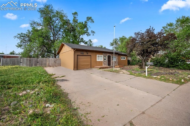 view of front of house featuring an attached garage, fence, concrete driveway, and stucco siding