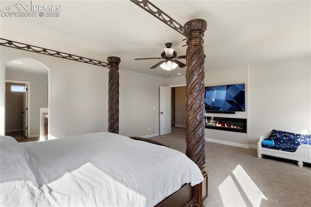 bedroom featuring a large fireplace, carpet floors, ceiling fan, and baseboards