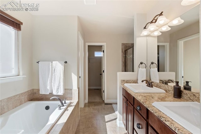 bathroom with a bath, double vanity, a sink, and a walk in closet