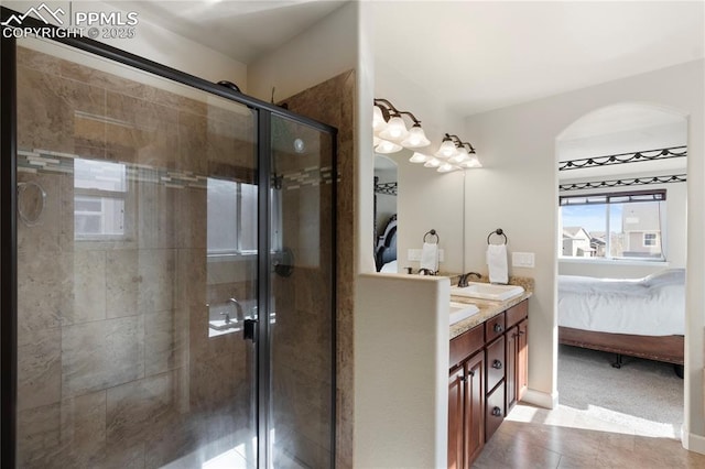 ensuite bathroom with double vanity, tile patterned floors, ensuite bathroom, a shower stall, and a sink