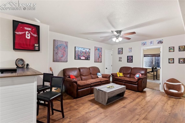 living room featuring a textured ceiling, wood finished floors, and a ceiling fan