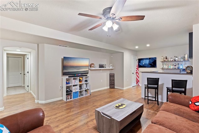 living room with a dry bar, baseboards, ceiling fan, wood finished floors, and recessed lighting