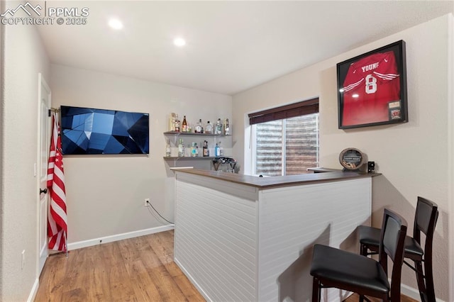 bar featuring light wood-type flooring, baseboards, a dry bar, and recessed lighting