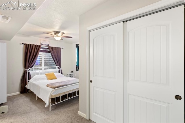 bedroom featuring a closet, light colored carpet, visible vents, a ceiling fan, and baseboards