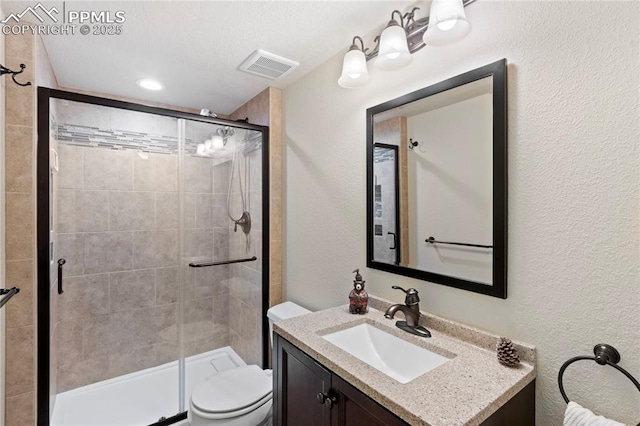 full bath with a textured wall, toilet, vanity, visible vents, and a stall shower