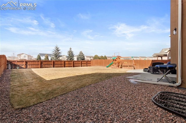 view of yard featuring a patio, a playground, and a fenced backyard