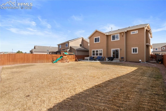 back of house featuring a playground, a yard, stucco siding, a patio area, and a fenced backyard