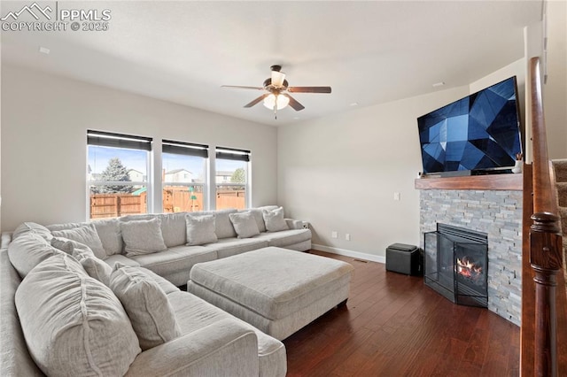 living area with visible vents, baseboards, dark wood finished floors, a ceiling fan, and a stone fireplace