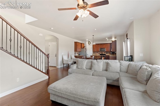 living room with dark wood-style floors, baseboards, stairway, and arched walkways