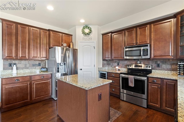 kitchen featuring beverage cooler, stainless steel appliances, dark wood-style flooring, a center island, and light stone countertops