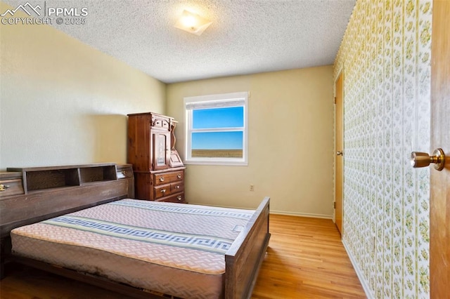 bedroom featuring light wood-style floors, baseboards, and a textured ceiling