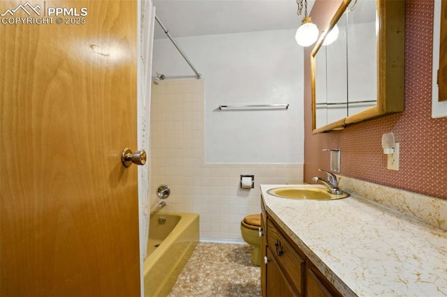 full bath with bathtub / shower combination, toilet, a wainscoted wall, vanity, and tile walls