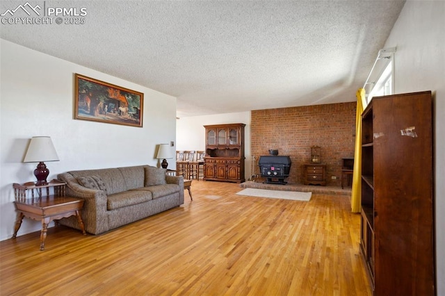 living room with a textured ceiling, light wood-type flooring, and a wood stove