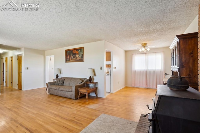 living area with light wood-style floors, ceiling fan, a textured ceiling, and baseboards