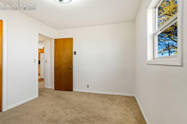 unfurnished bedroom featuring carpet, freestanding refrigerator, and baseboards