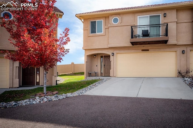 view of front of home featuring a balcony, driveway, an attached garage, and stucco siding