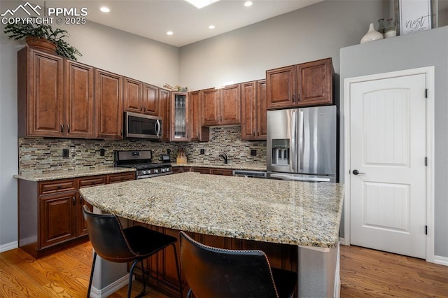 kitchen featuring stainless steel appliances, light wood-style floors, backsplash, and a breakfast bar area