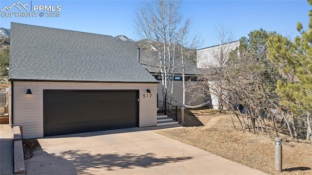 view of front of house featuring a detached garage and roof with shingles