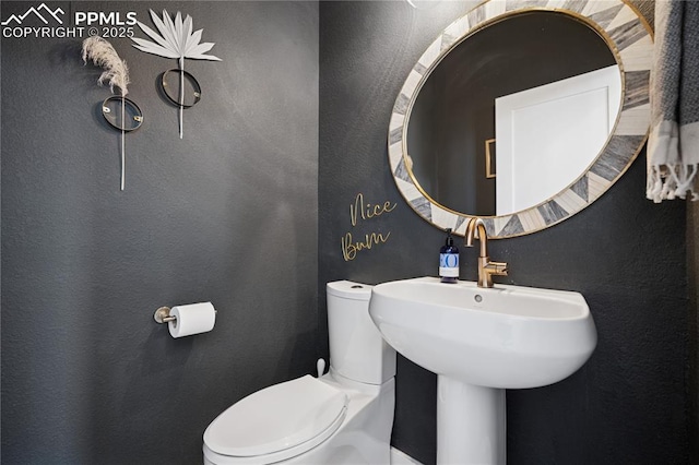 half bath featuring toilet and a textured wall