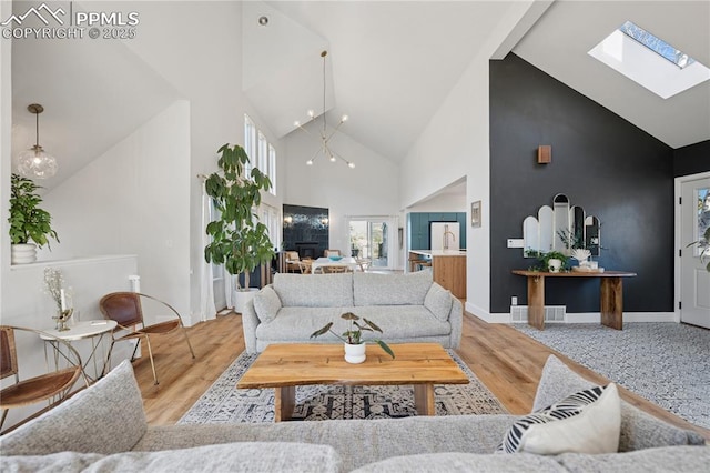 living area featuring high vaulted ceiling, a skylight, wood finished floors, and visible vents