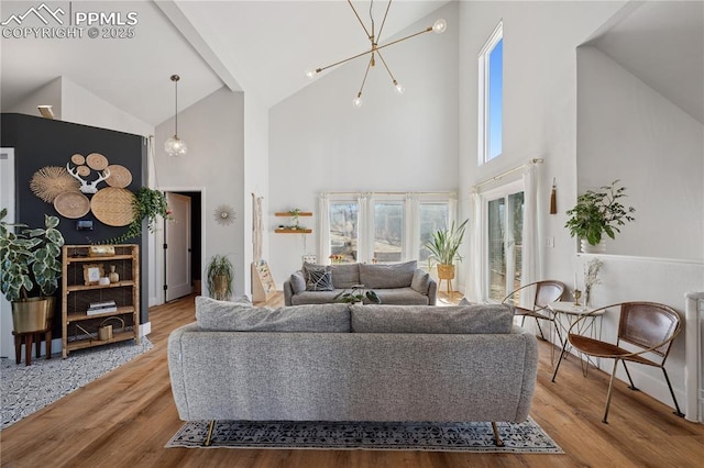 living area with a chandelier, wood finished floors, and lofted ceiling