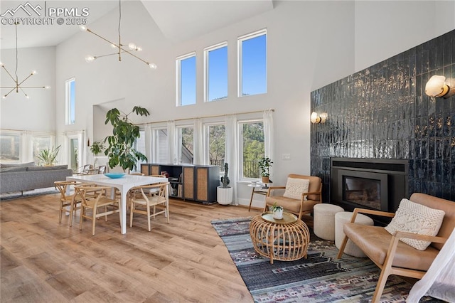 interior space with wood finished floors, baseboards, vaulted ceiling, a glass covered fireplace, and an inviting chandelier