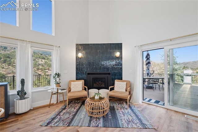 sitting room featuring baseboards, visible vents, a tile fireplace, wood finished floors, and a high ceiling