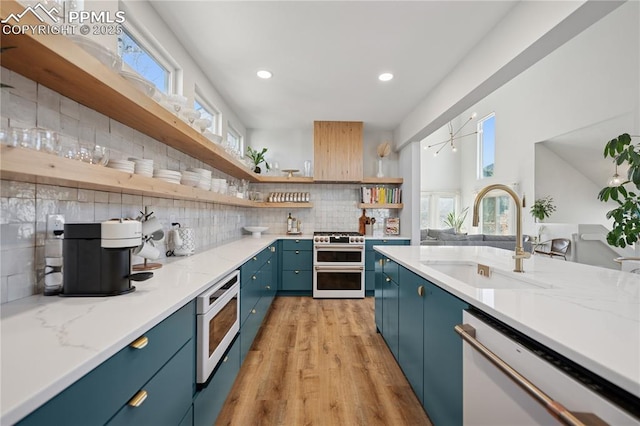 kitchen featuring open shelves, tasteful backsplash, a sink, blue cabinets, and white appliances