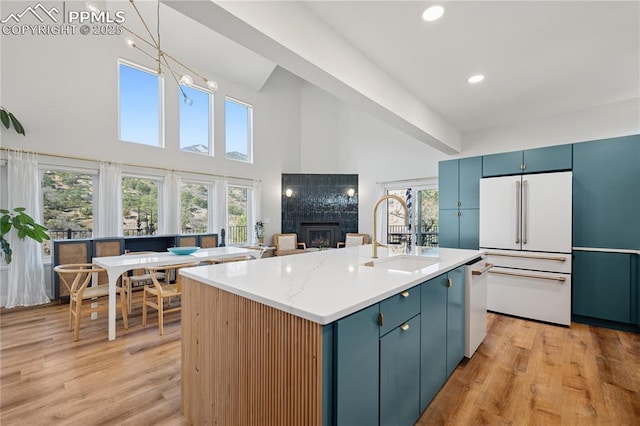 kitchen featuring blue cabinets, white appliances, a fireplace, and a sink