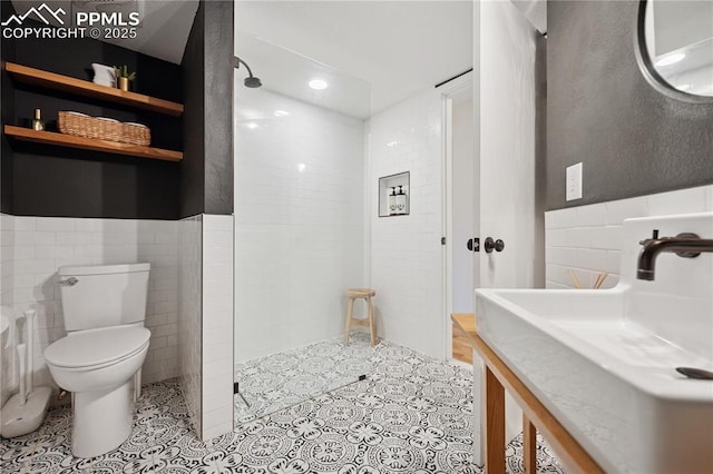 bathroom with a walk in shower, tile patterned flooring, toilet, tile walls, and wainscoting