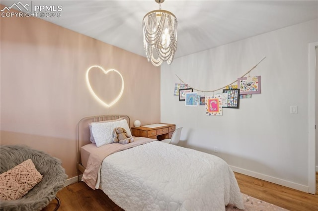 bedroom featuring a notable chandelier, baseboards, and wood finished floors