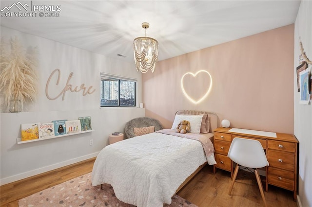 bedroom with a chandelier, wood finished floors, visible vents, and baseboards