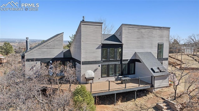 rear view of house featuring a chimney and a wooden deck